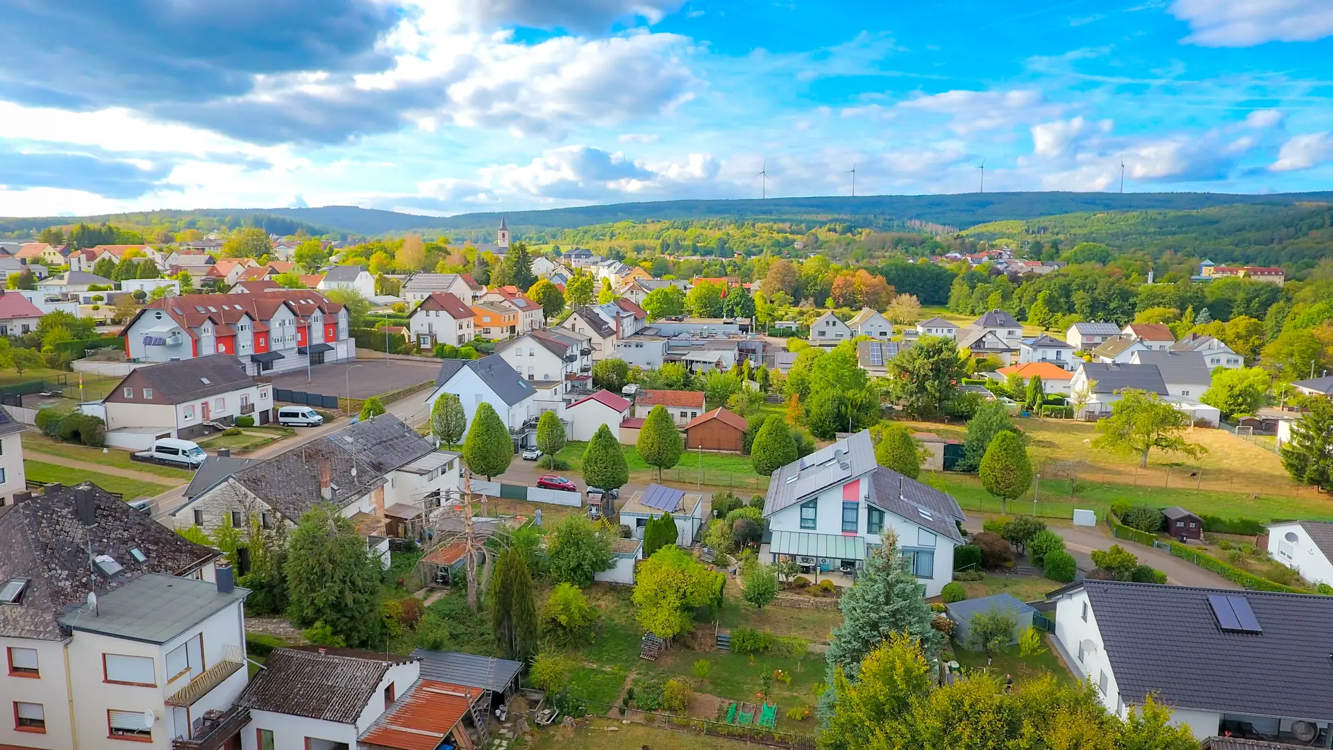 Luftaufnahme von Weiskirchen mit Wohnhäusern, Kirche und den Wäldern des Hochwalds